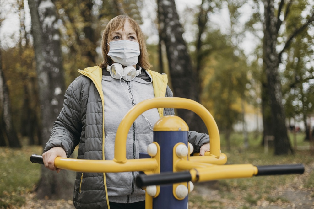 senior woman with medical mask working out outdoors
