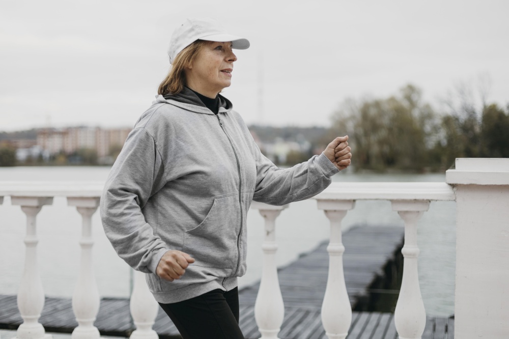 side view older woman jogging outdoors