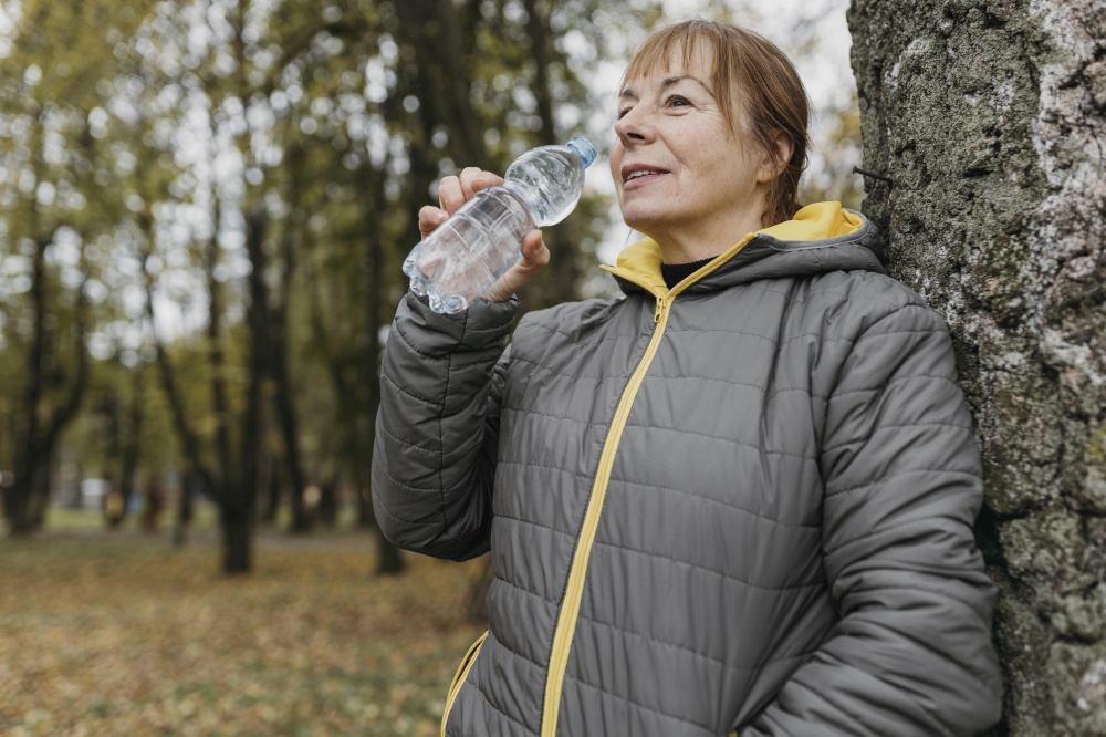 side view senior woman drinking water after working out outdoors
