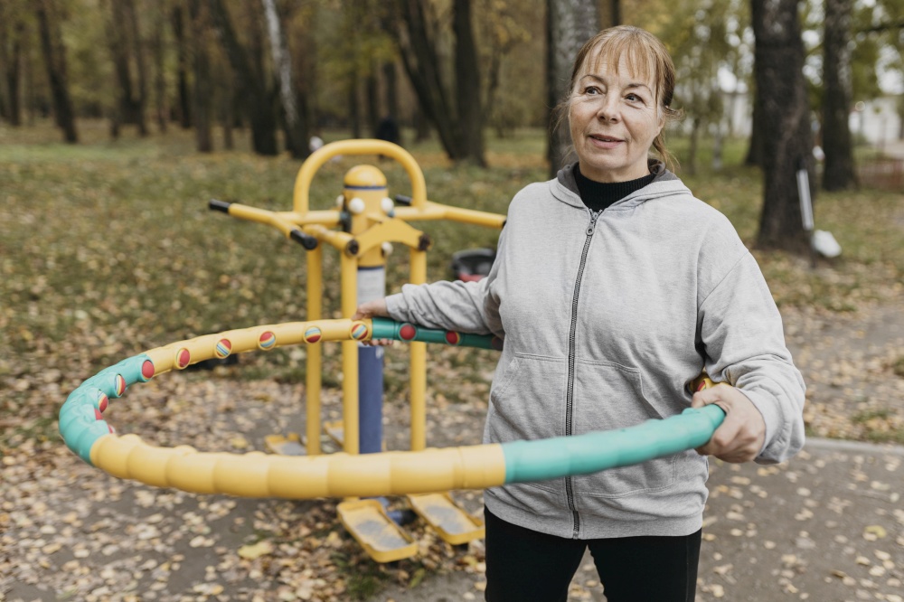 smiley elder woman outside working out with equipment