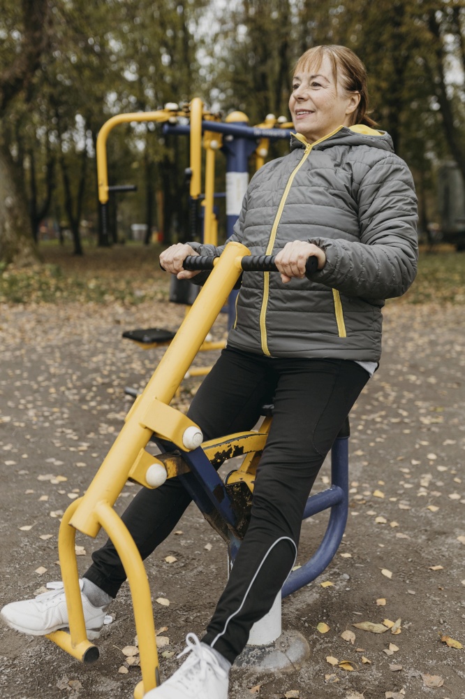 smiley elder woman working out with equipment outdoors