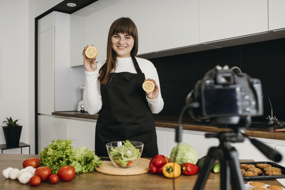 smiley female blogger recording herself while preparing salad