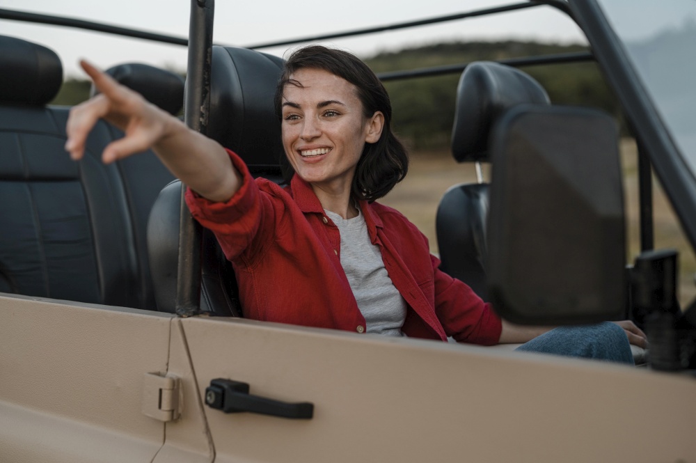 smiley woman pointing while traveling alone by car