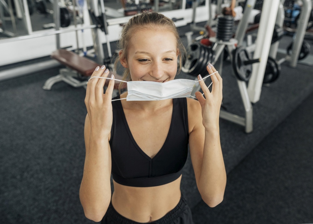 smiley woman putting her medical mask gym