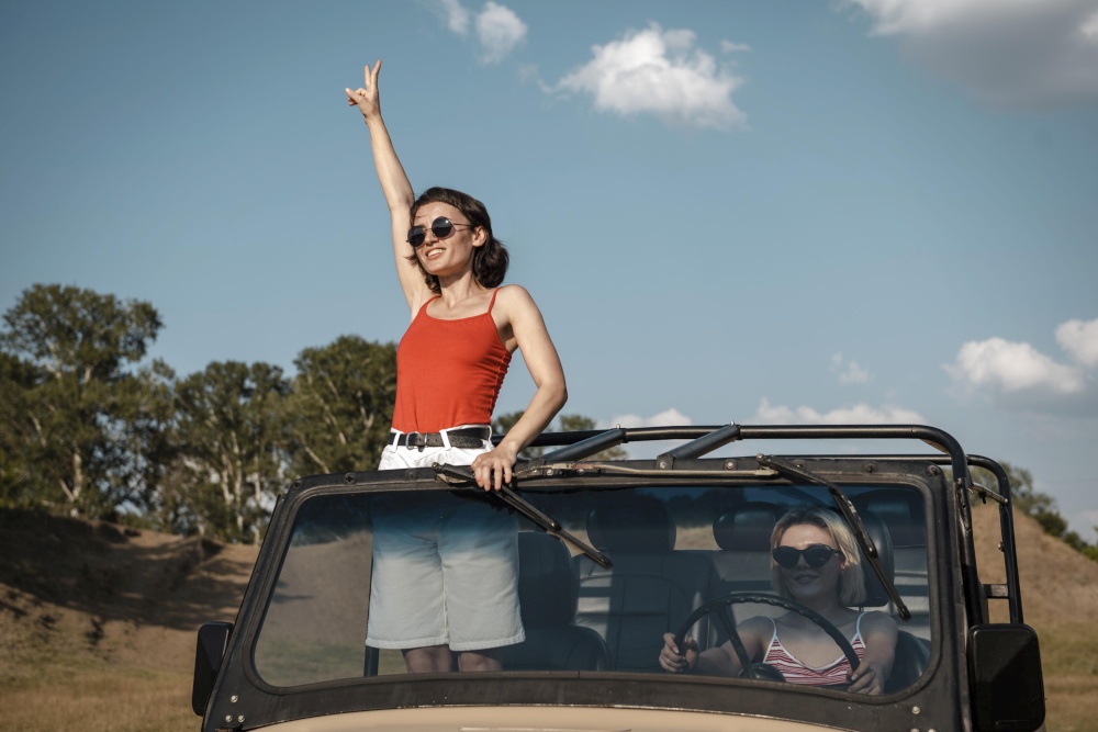 woman with sunglasses having fun while traveling by car