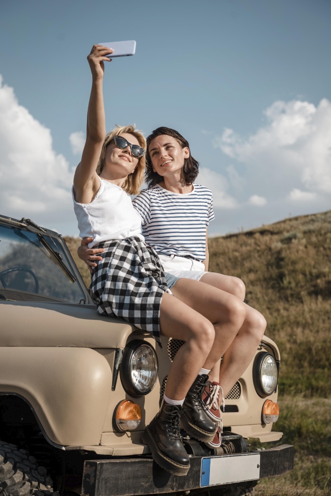 women taking selfie while traveling by car
