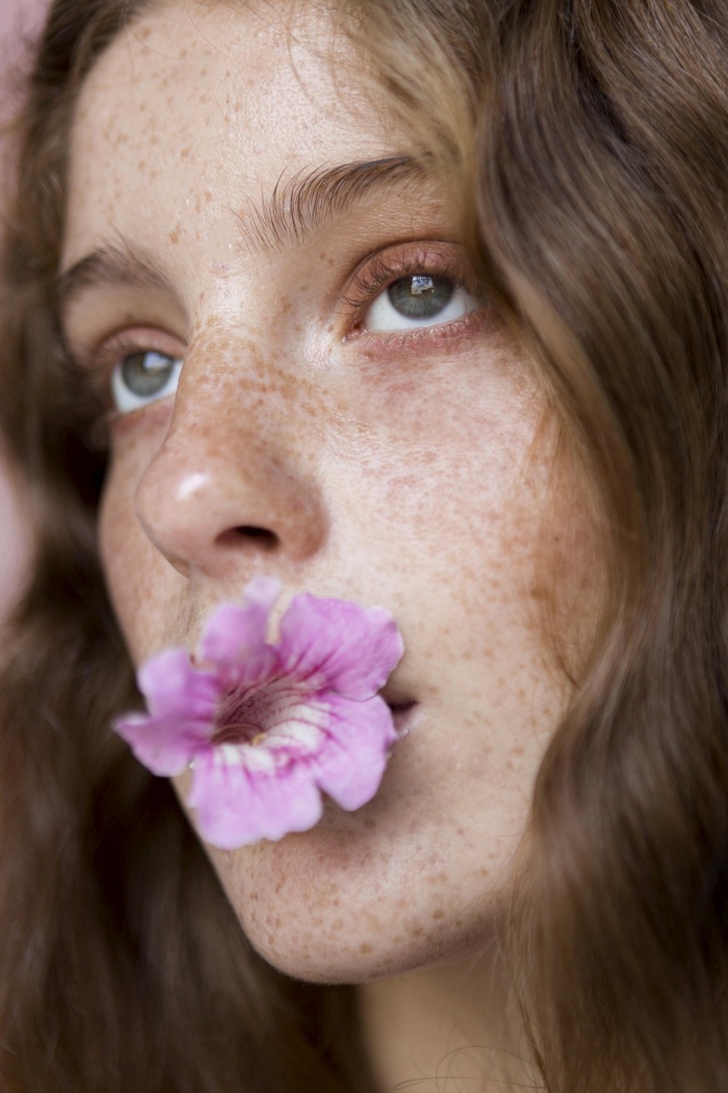 portrait freckled woman with flower her mouth close up