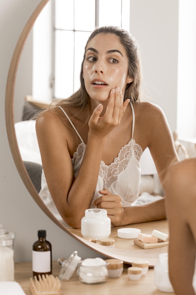 woman applying cream looking into mirror