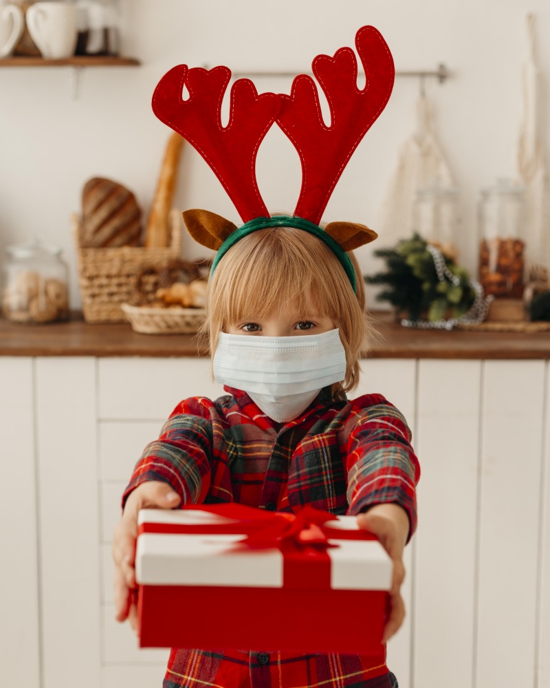 boy with medical mask holding christmas present