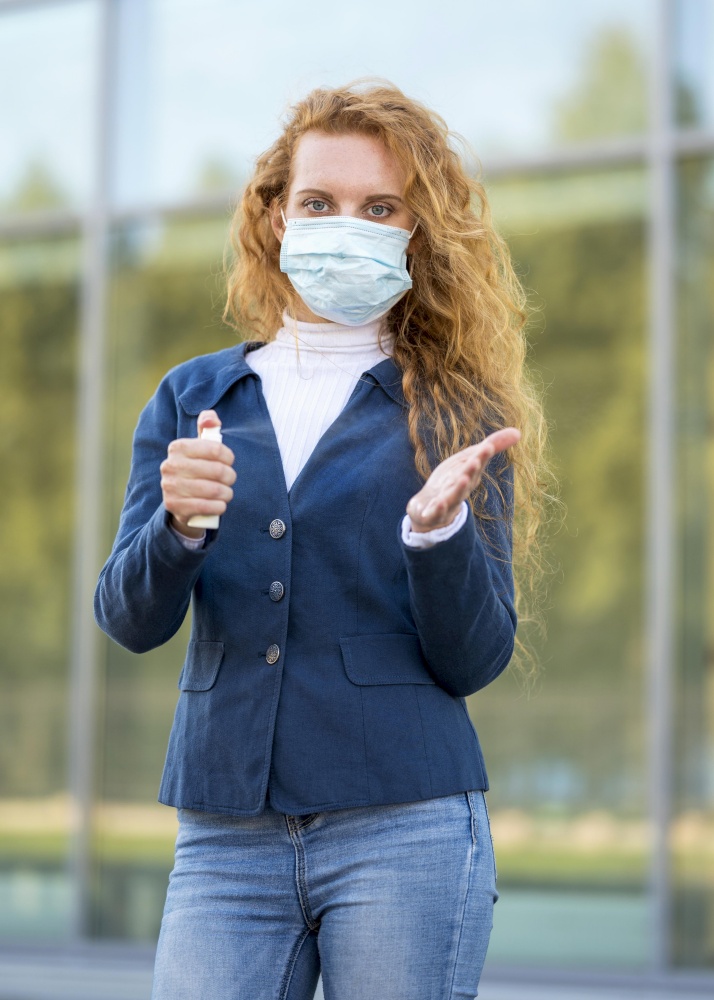 businesswoman using hand sanitizer wearing medical mask