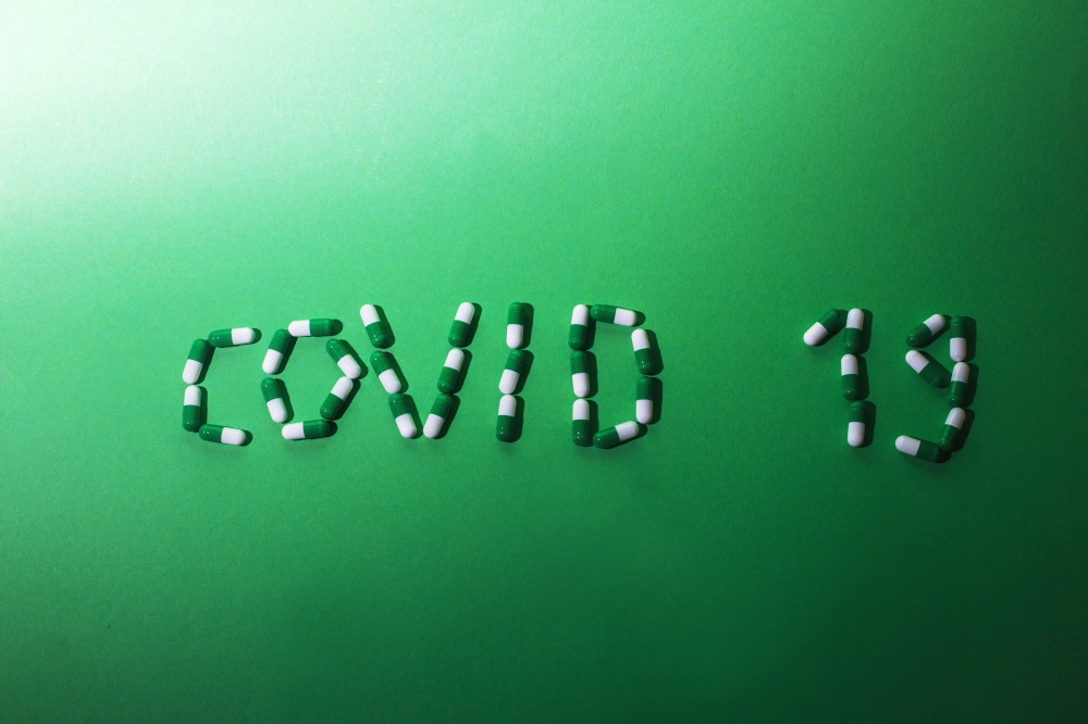 Inscription Covid 19 from letters made of pills on green background. Corona virus concept.. Inscription Covid 19 from letters made of pills on a green background. Corona virus concept.