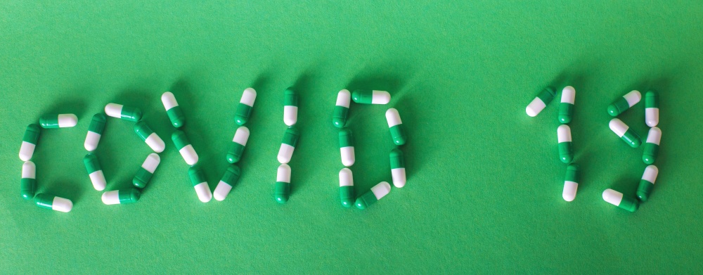 Inscription Covid 19 from letters made of pills on green background. Corona virus concept. banner. Inscription Covid 19 from letters made of pills on a green background. Corona virus concept. banner
