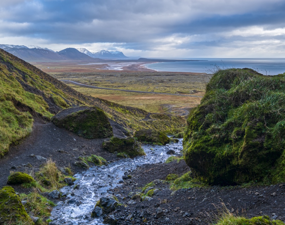 View during auto trip in West Iceland highlands, Snaefellsnes peninsula, Snaefellsjokull National Park. Spectacular volcanic tundra view from Raudfeldsgja Gorge along stream to ocean coast.