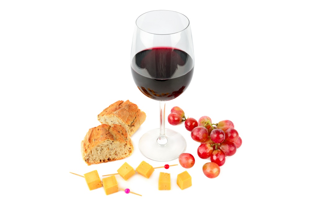 A glass of red wine , bunch of grapes , baguette and cheese isolated on a white background.