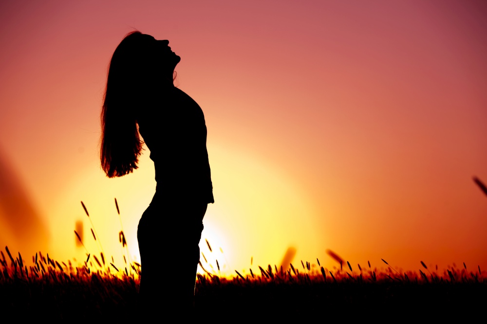Silhouette of a young woman relaxing on a beautiful sunset of a summer day