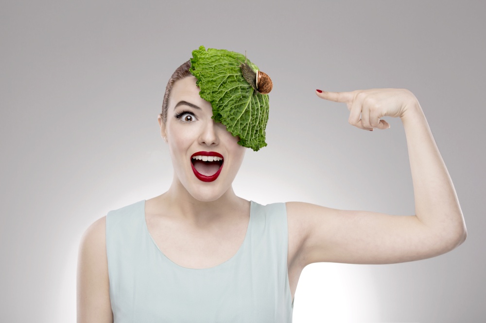 Portrait of a woman illustrating a vegan concept with a cabbage on the head with a snail on it. Vegan Girl