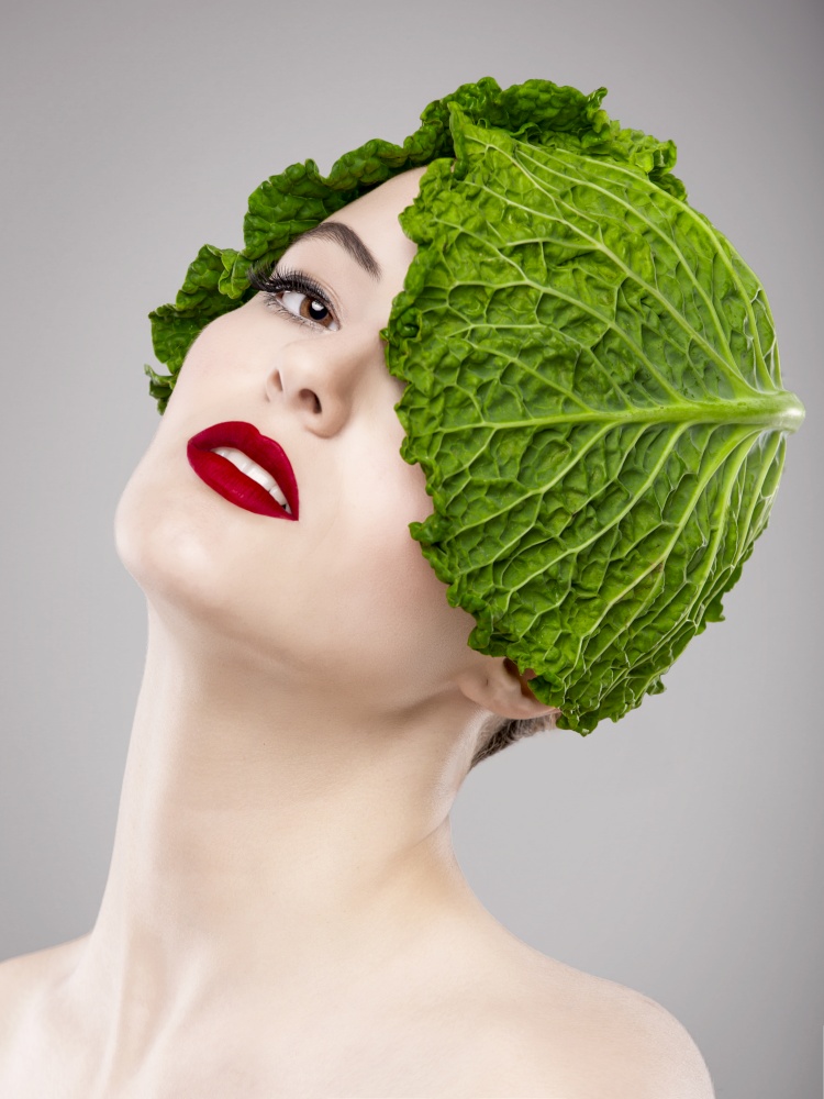 Portrait of a woman illustrating a vegan concept with a cabbage on the head. Vegan Girl
