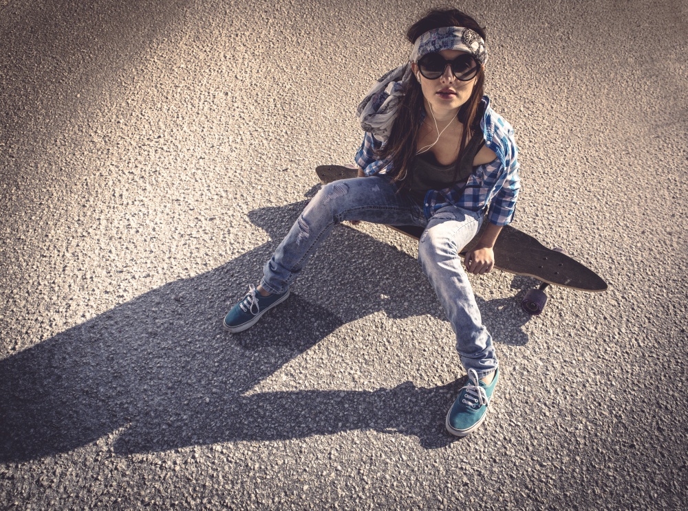 Beautiful young woman sitting over a skateboard. Skater Girl