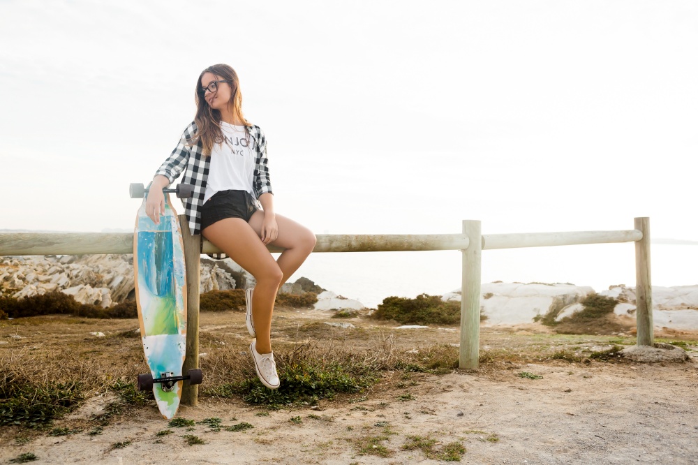 Beautiful and fashion young woman posing with a skateboard