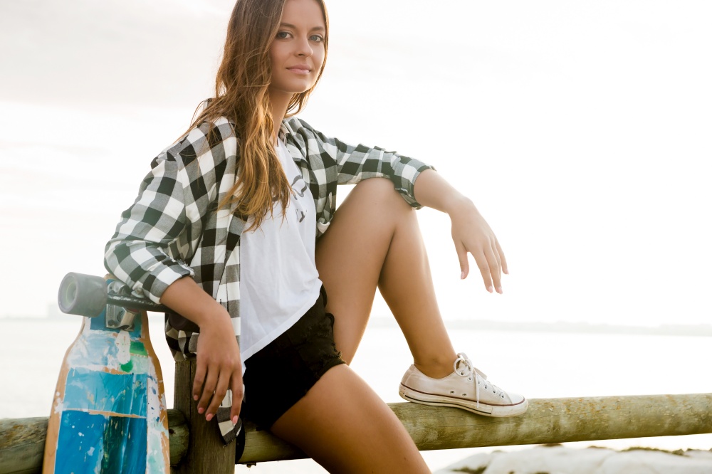 Beautiful and fashion young woman posing with a skateboard