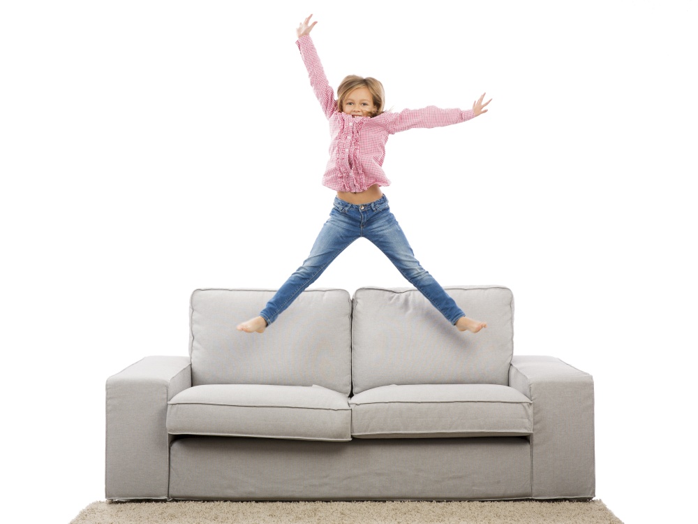 Cute blonde girl jumping over the sofa