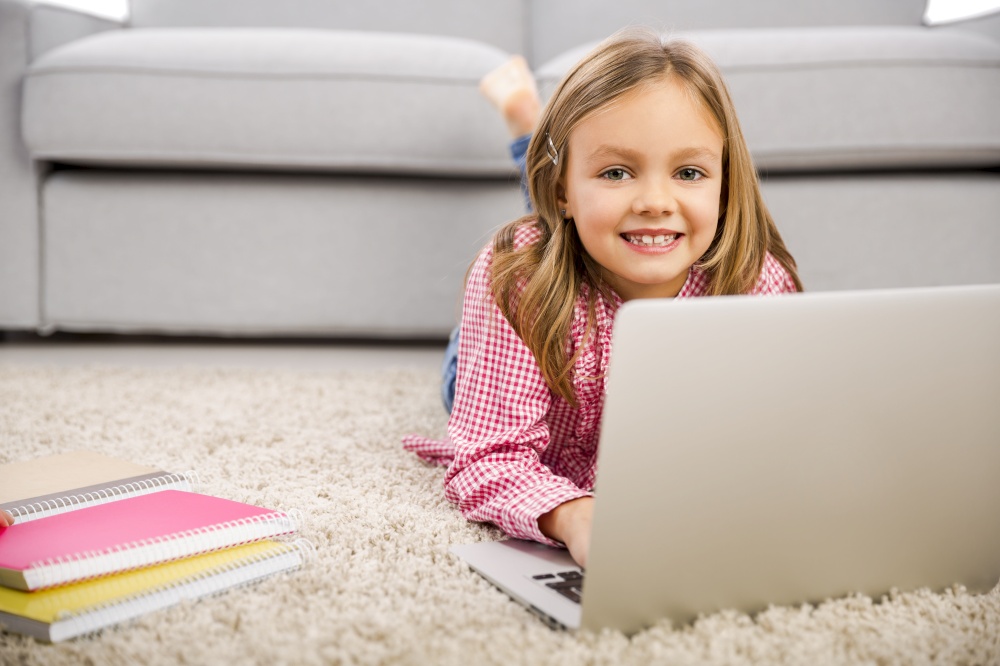 Happy little girl at home working with a laptop