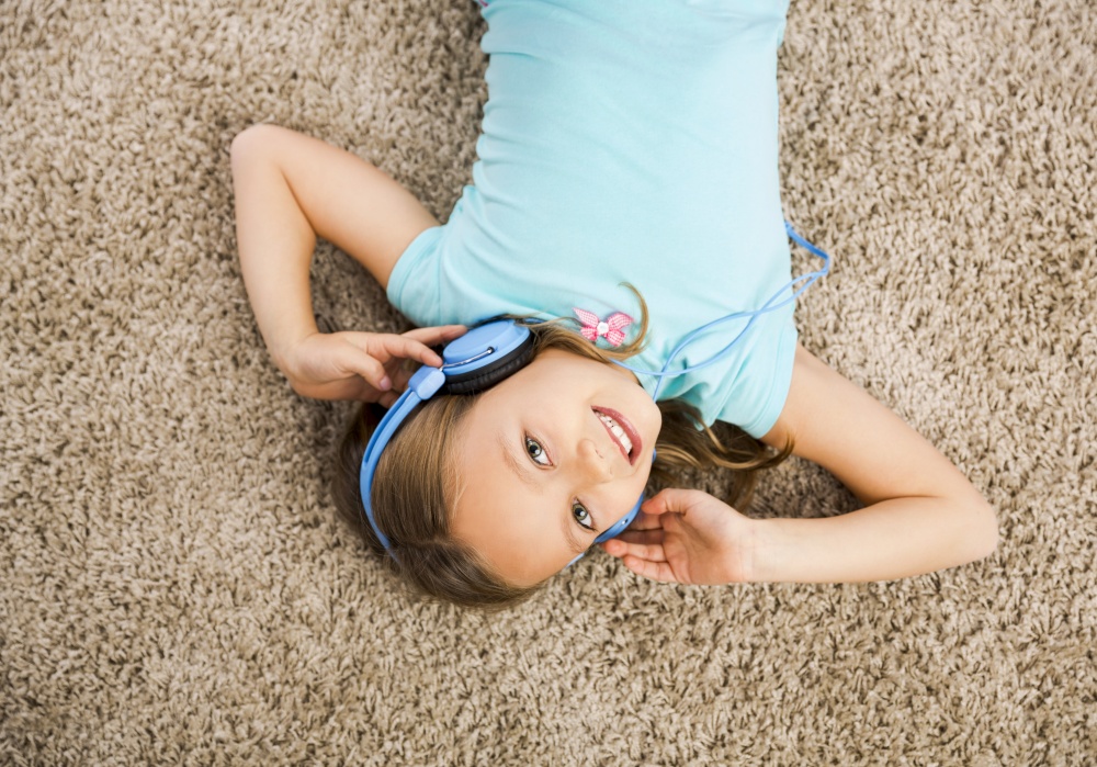 Little blonde girl at home listen music with headphones