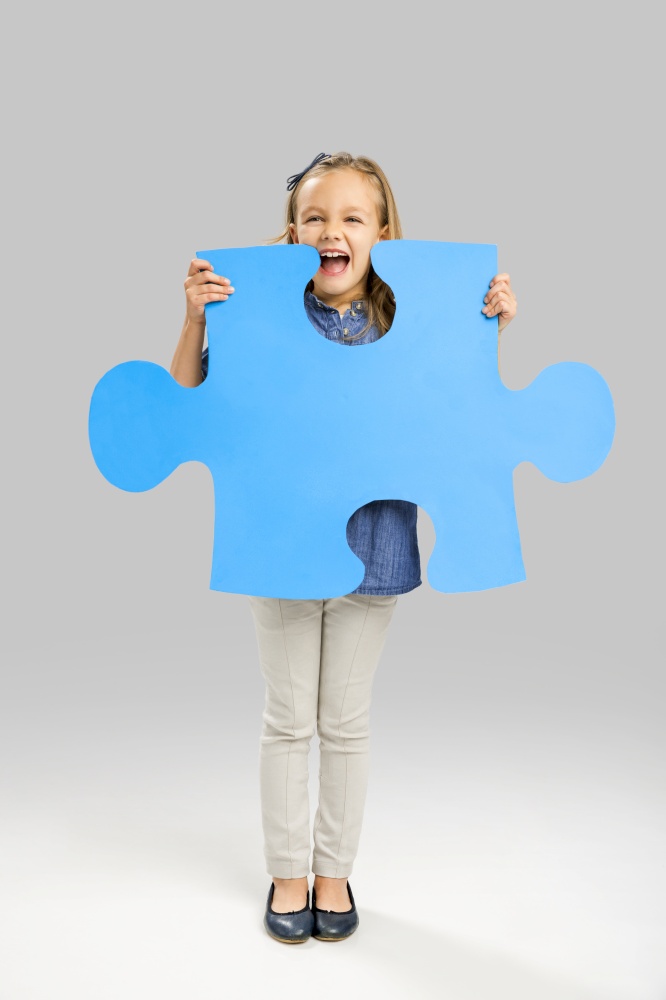 Beautiful little girl holding a big blue Puzzle