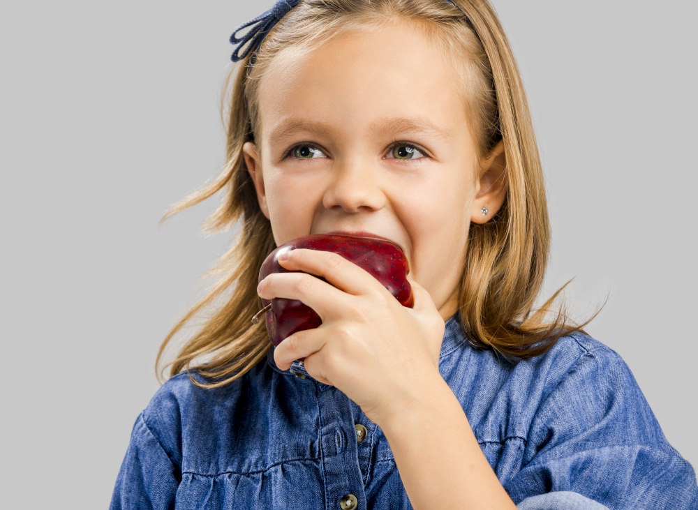 Studio portrait of a beautiful cute girl holding a fresh red apple