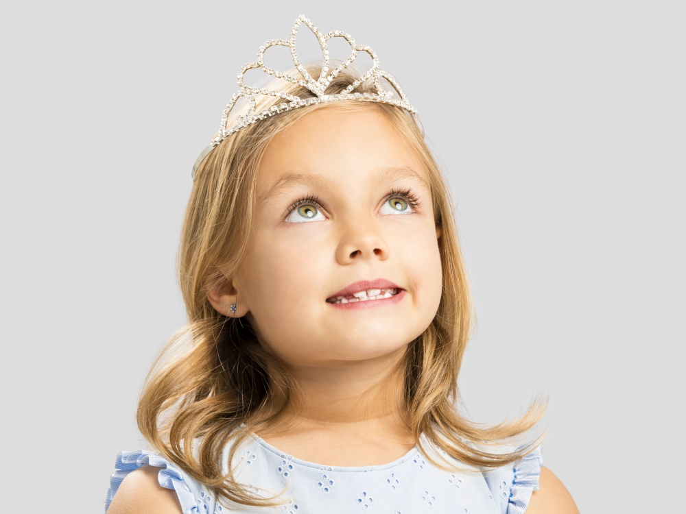 Portrait of a cute little girl wearing a princess crown and making a dreamy face