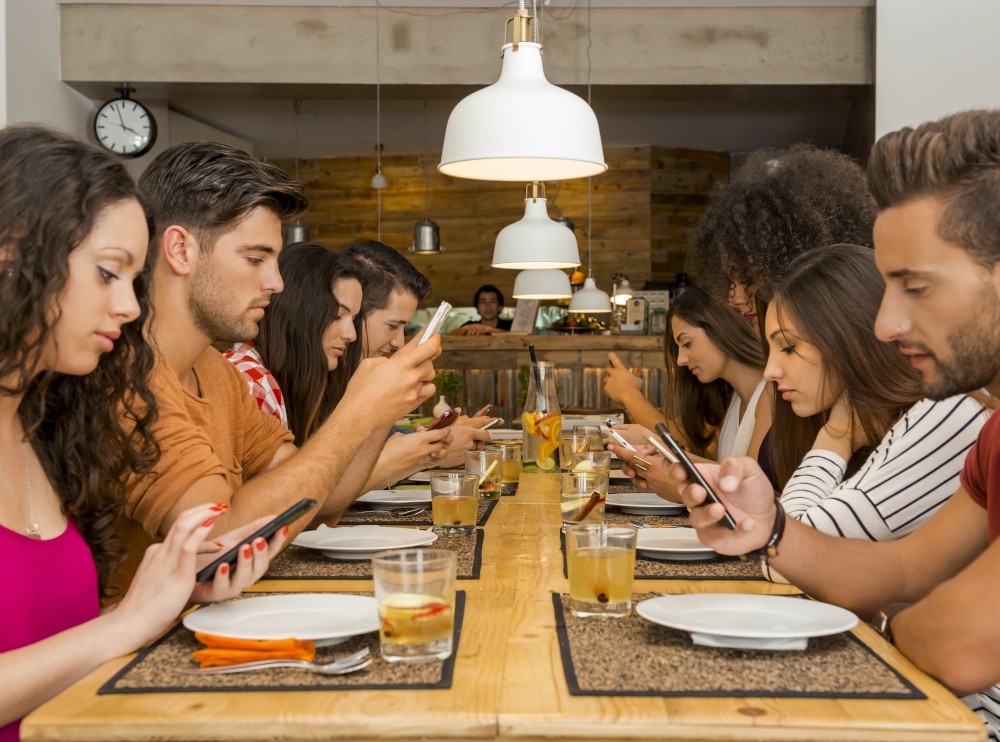 Group of friends at a restaurant with all people on the table occupied with cellphones