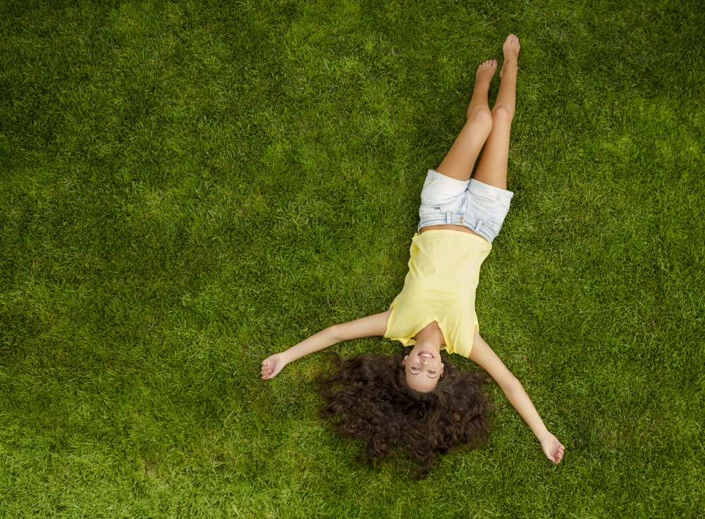 Outdoor portrait of a beautiful young woman lying on the grass