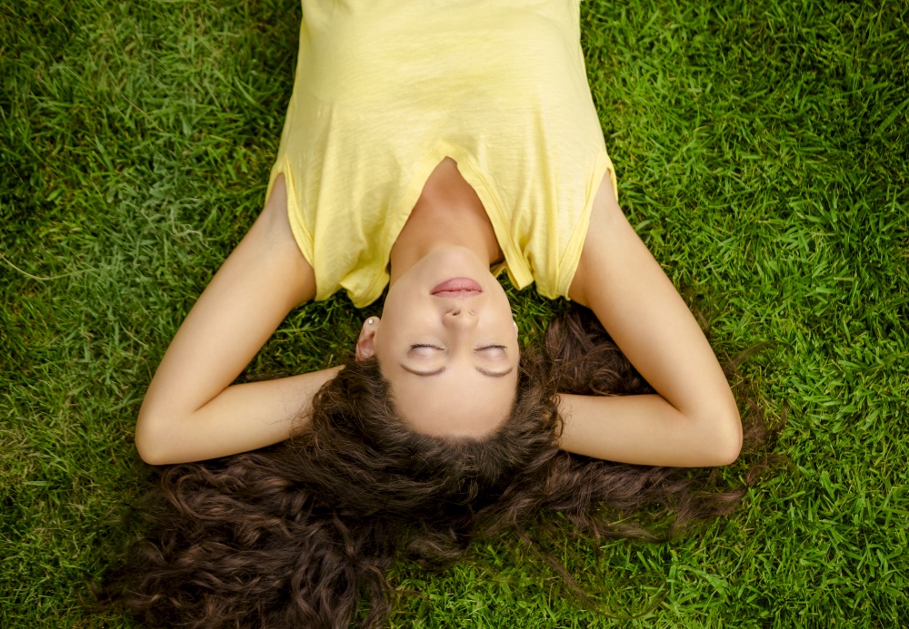 Portrait of a beautiful and happy young woman lying on the grass