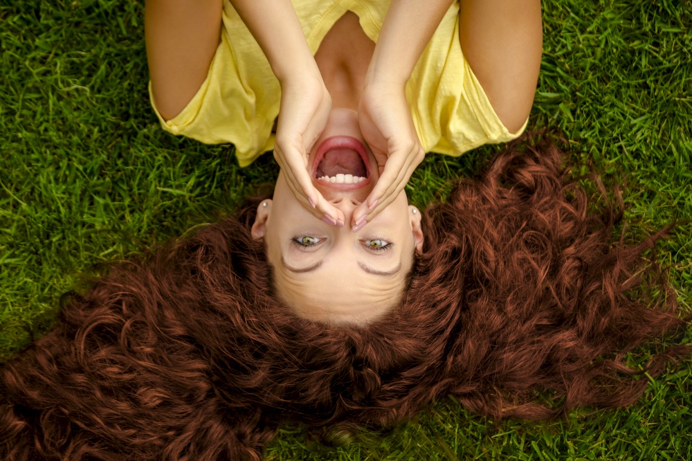 Portrait of a beautiful readhead woman lying on the grass