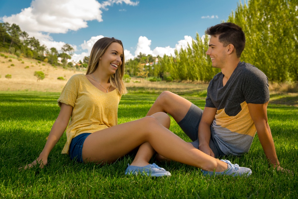 Young couple sitting on the grass and having fun