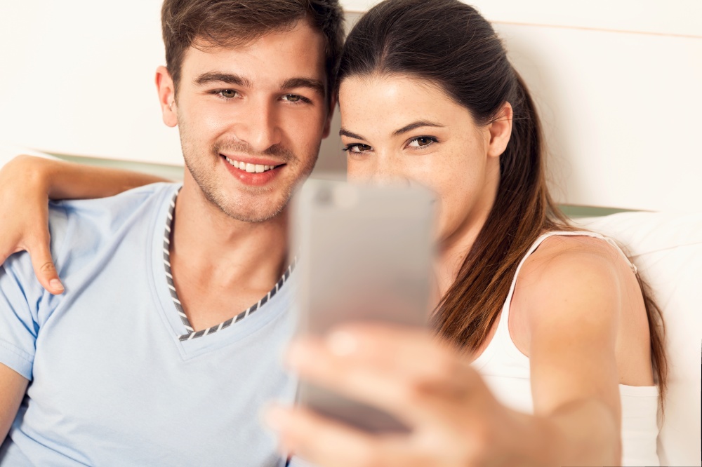 Young couple on bed making selfies with a phone