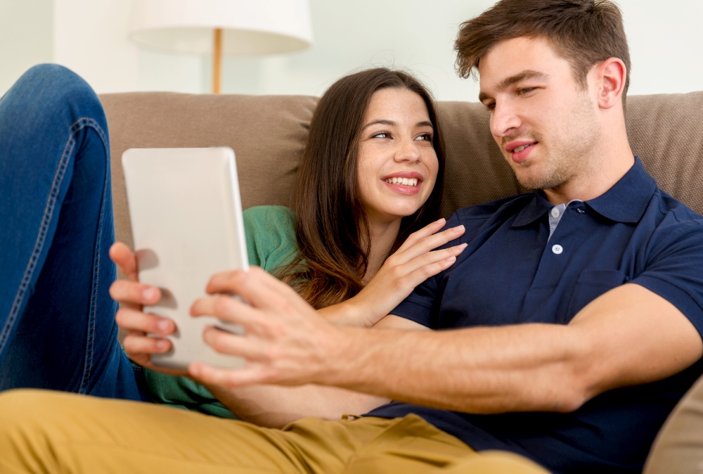 Young couple sitting on the sofa and watching something on a tablet