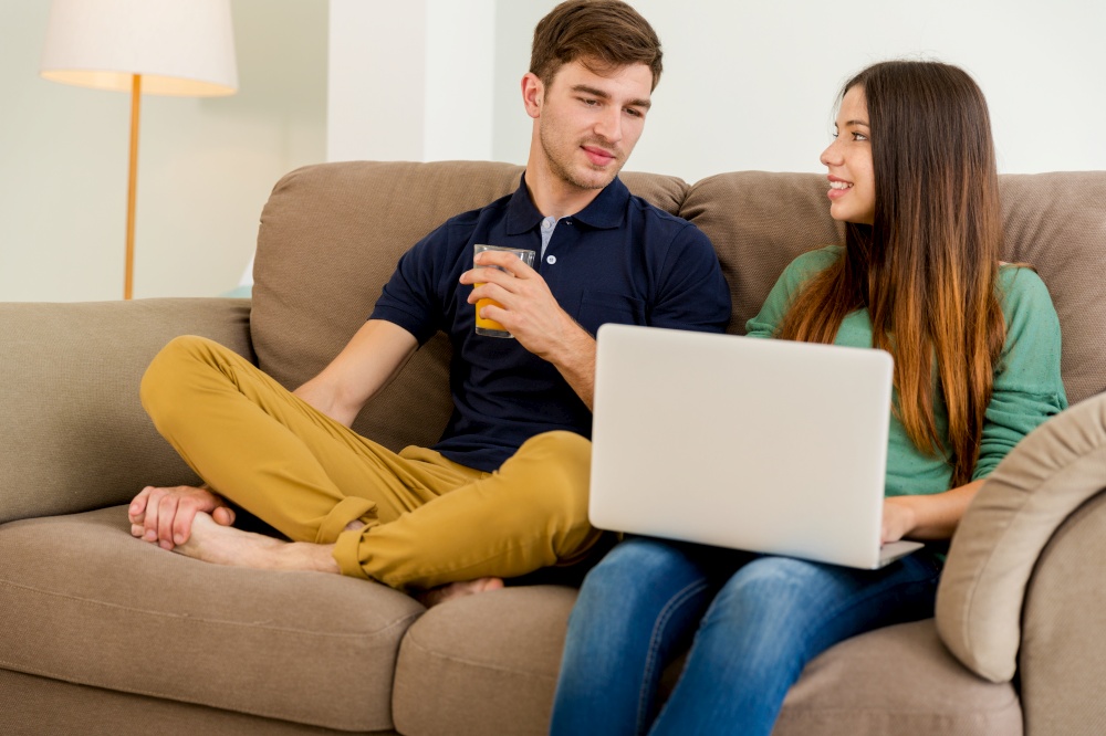 Young couple sitting on the sofa and watching something on a laptop