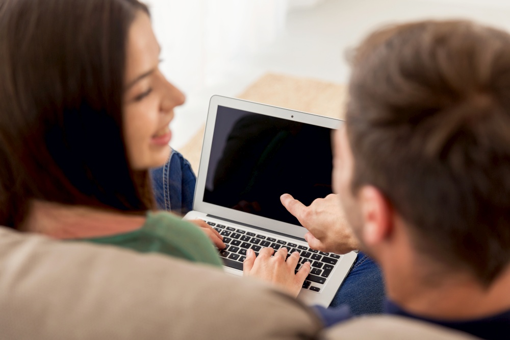 Young couple sitting on the sofa and watching something on a laptop