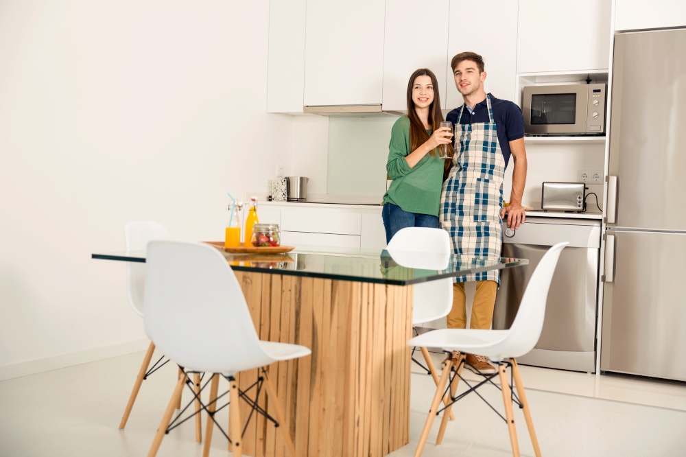 Young couple on the kitchen enjoying a  glass of white wine