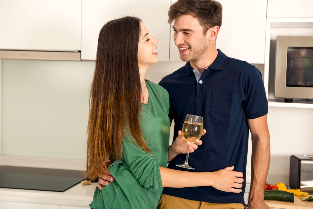 Young couple on the kitchen enjoying a  glass of white wine