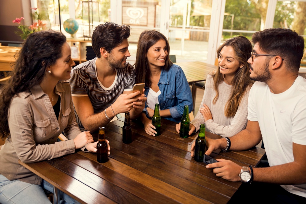 A group of friends at the bar drinking a beer