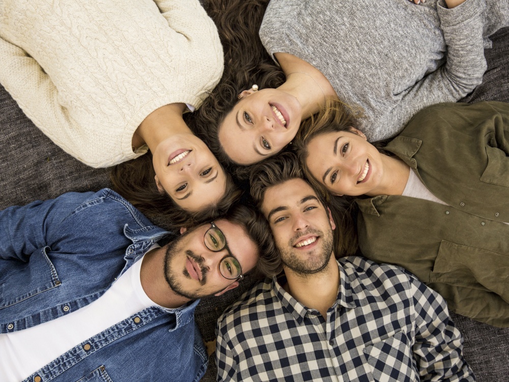 Top view of a group of friends lying on floor and looking at camera
