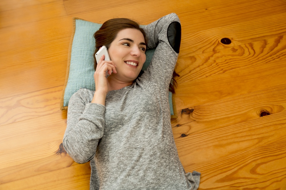 Beautiful woman lying on the floor and talking at phone