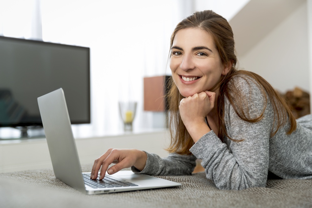 Beautiful woman working at home with a laptop while listen music