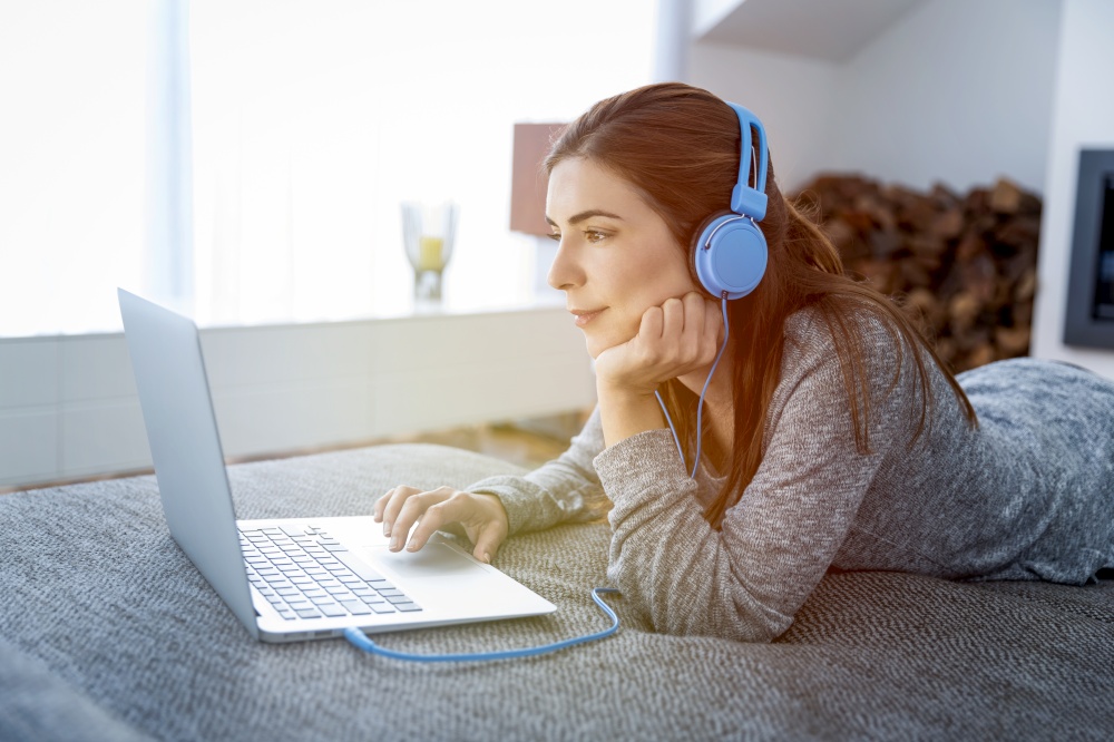 Beautiful woman working at home with a laptop while listen music
