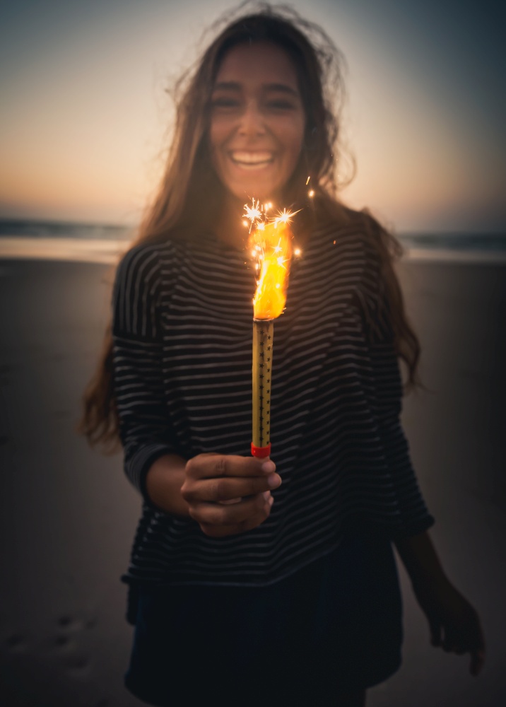 Teenage girl on the beach holding Fireworks