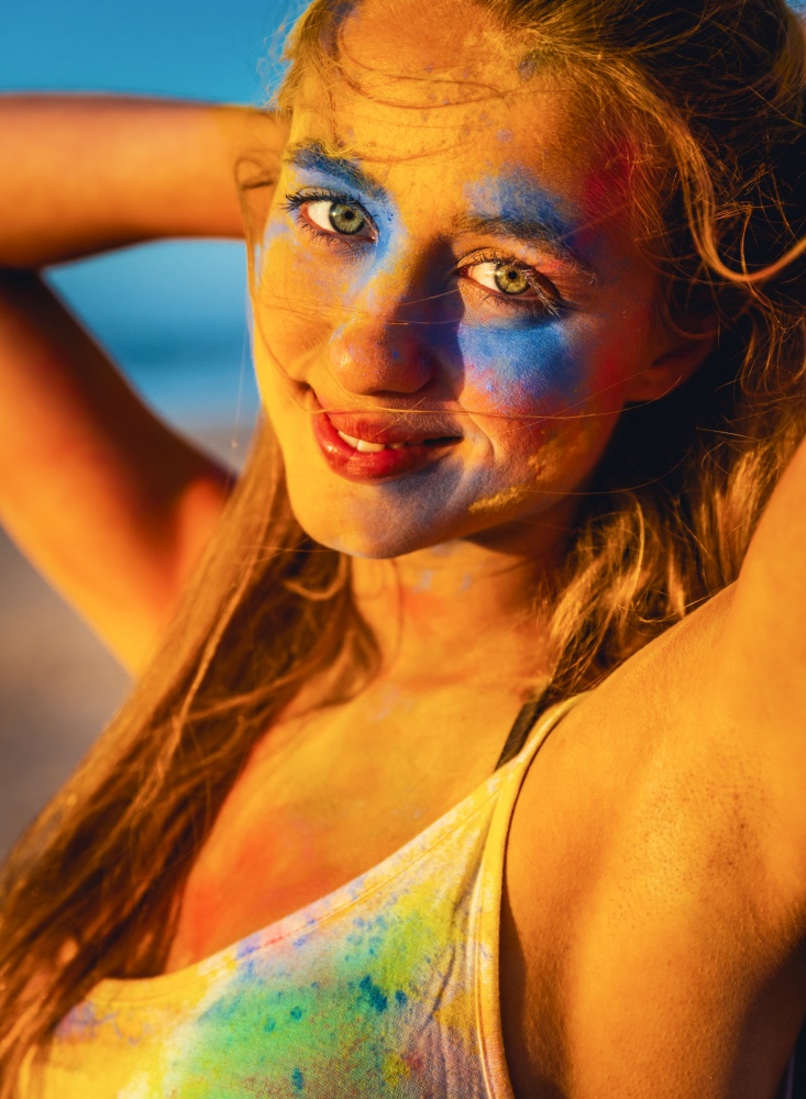 Portrait of a beautiful girl full of colored powder on the face