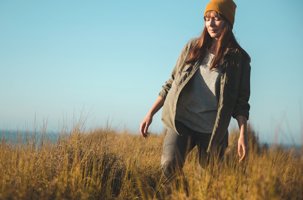 Beautiful woman with a yellow cap and walking over high grass