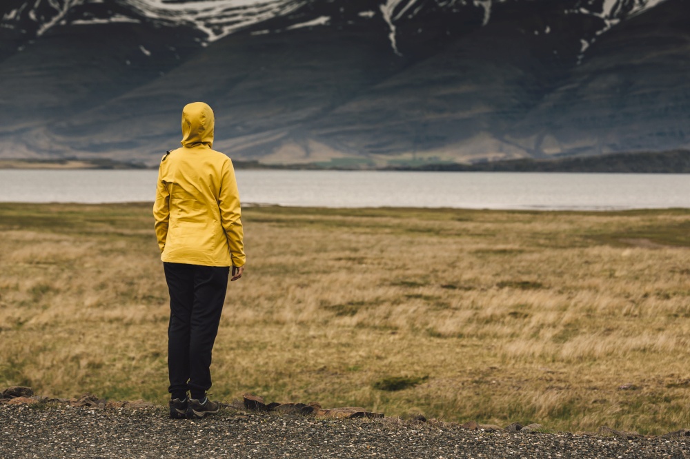 Woman in yellow contemplating the landscape; Iceland